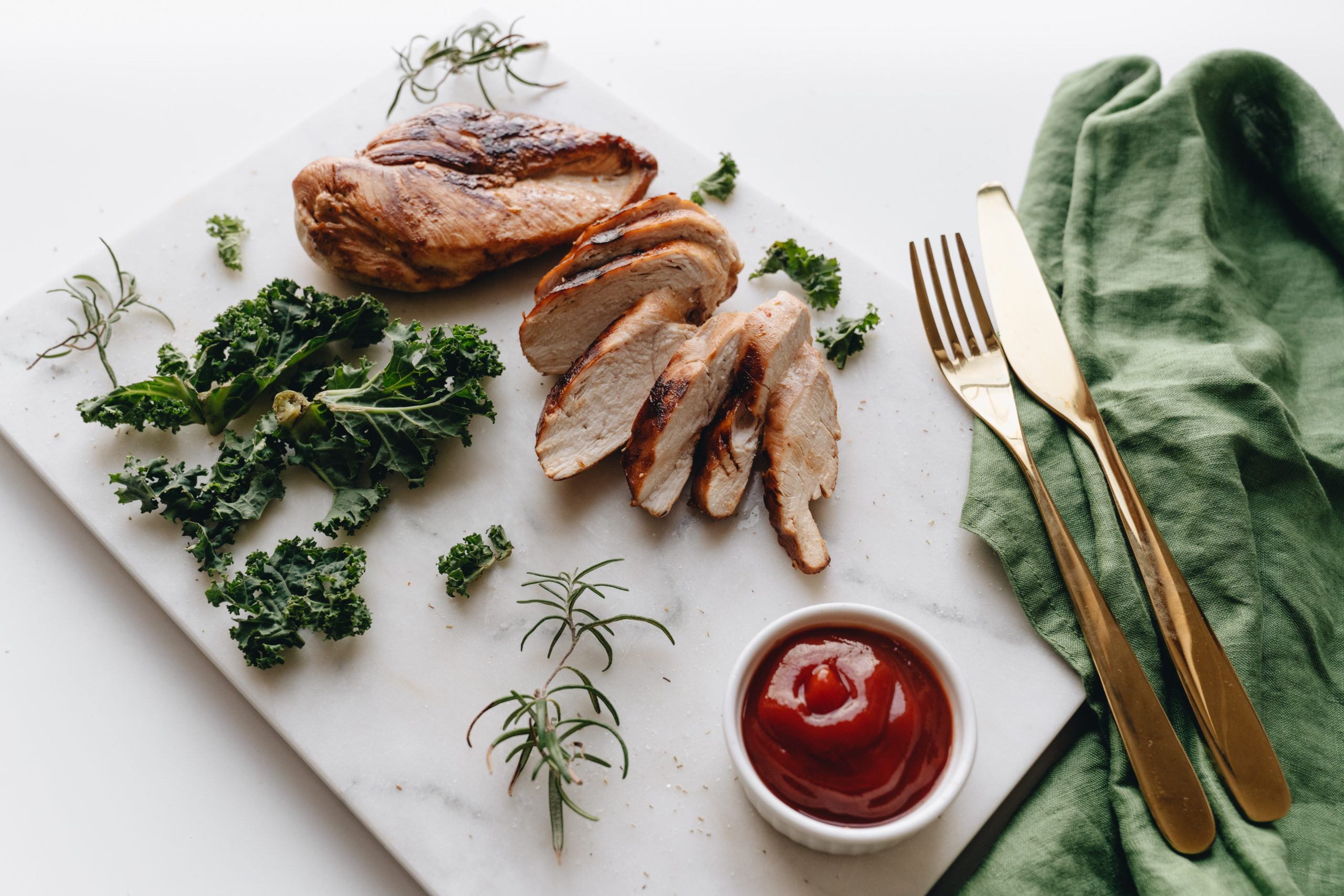 Two chicken breast on a marble cutting board. Chicken breasts are a good source of niacin and can be included in our healthy diets.
